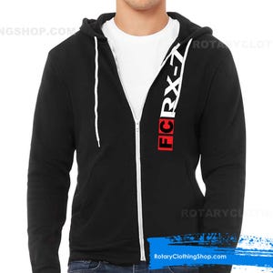 May include: Black zippered hoodie with a white zipper and white drawstring. The hoodie has a red and white graphic on the front that says "FC RX-7".