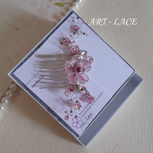 A delicate pink flower hair comb in silver finish, Japanese Kanzashi style, The central flower size 3 cm diameter. Around that is a cluster of petals, crystals and tiny seed beads. Handmade wire resin pink flowers and petals.