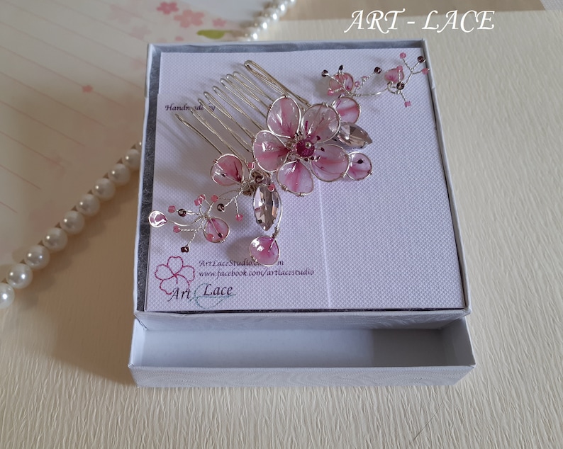 A delicate pink flower hair comb in silver finish, Japanese Kanzashi style, The central flower size 3 cm diameter. Around that is a cluster of petals, crystals and tiny seed beads. Handmade wire resin pink flowers and petals.