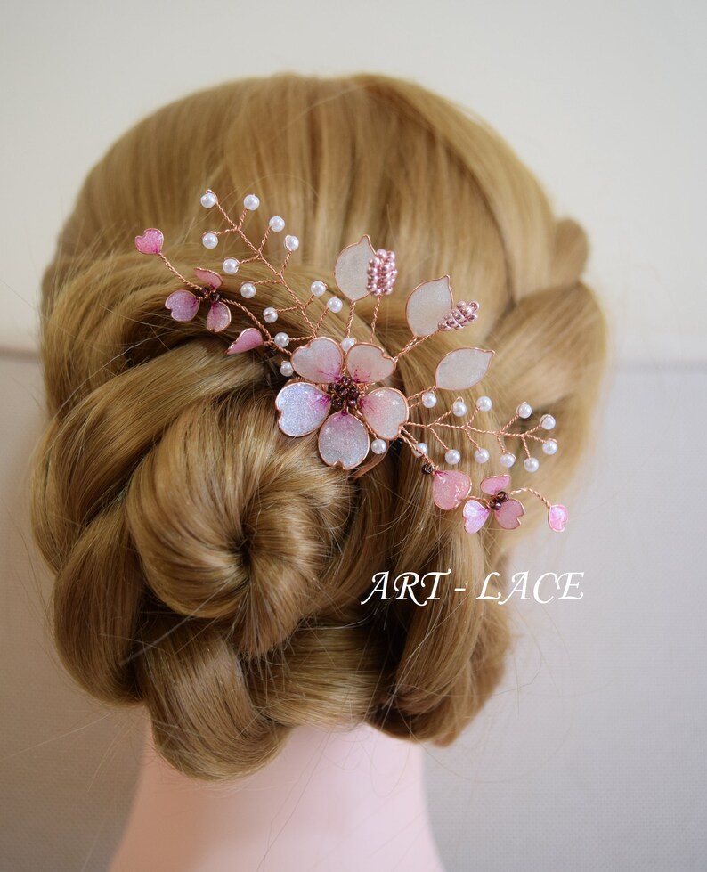 May include: A hair comb featuring delicate pink and white translucent flower petals, small white pearl-like beads, and thin copper-colored wire branches. The text ART-LACE is visible in the lower right corner of the image.