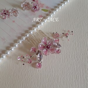 A delicate pink flower hair comb in silver finish, Japanese Kanzashi style, The central flower size 3 cm diameter. Around that is a cluster of petals, crystals and tiny seed beads. Handmade wire resin pink flowers and petals.