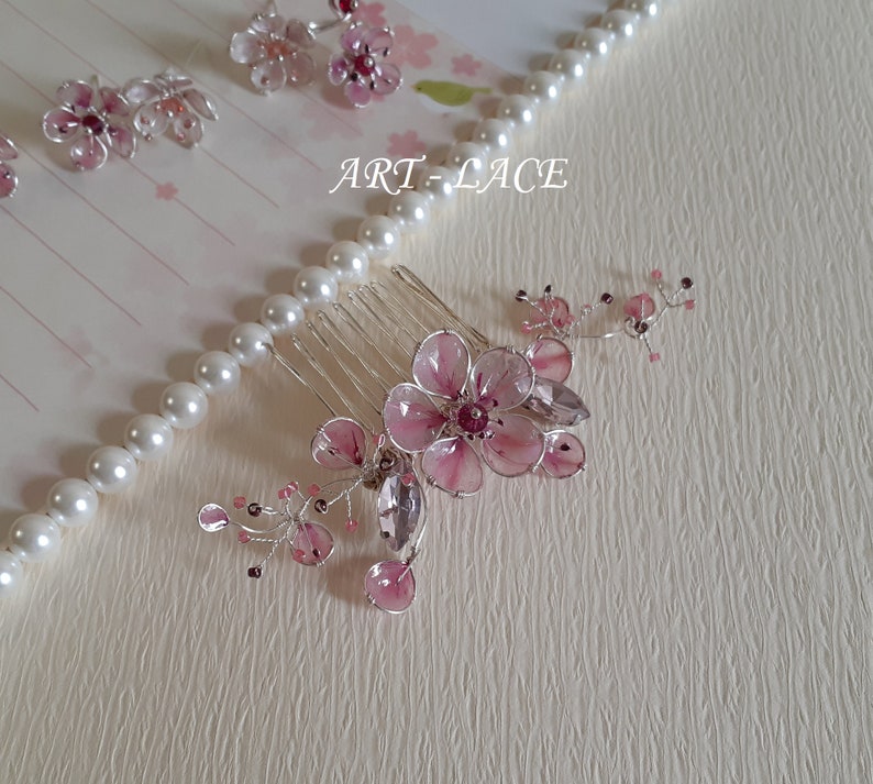 A delicate pink flower hair comb in silver finish, Japanese Kanzashi style, The central flower size 3 cm diameter. Around that is a cluster of petals, crystals and tiny seed beads. Handmade wire resin pink flowers and petals.