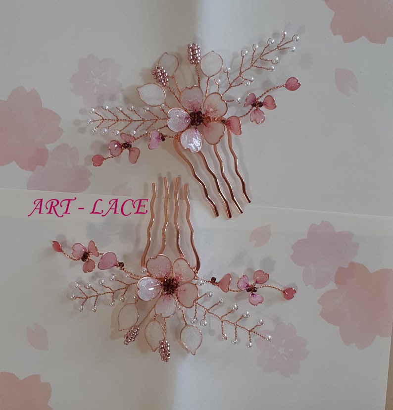 May include: Two hair combs featuring rose gold wire branches adorned with translucent pink and white resin flower petals, small white beads, and metallic pink seed beads. The text ART-LACE is printed in pink on the left side of the image.
