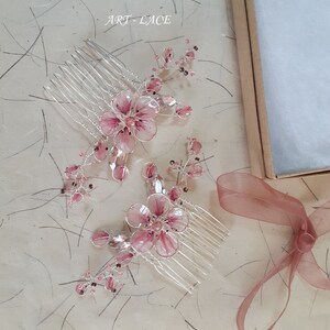 A delicate pink flower hair comb in silver finish, Japanese Kanzashi style, The central flower size 3 cm diameter. Around that is a cluster of petals, crystals and tiny seed beads. Handmade wire resin pink flowers and petals.