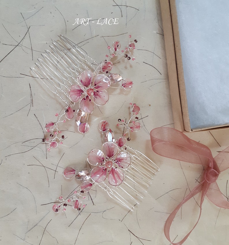 A delicate pink flower hair comb in silver finish, Japanese Kanzashi style, The central flower size 3 cm diameter. Around that is a cluster of petals, crystals and tiny seed beads. Handmade wire resin pink flowers and petals.