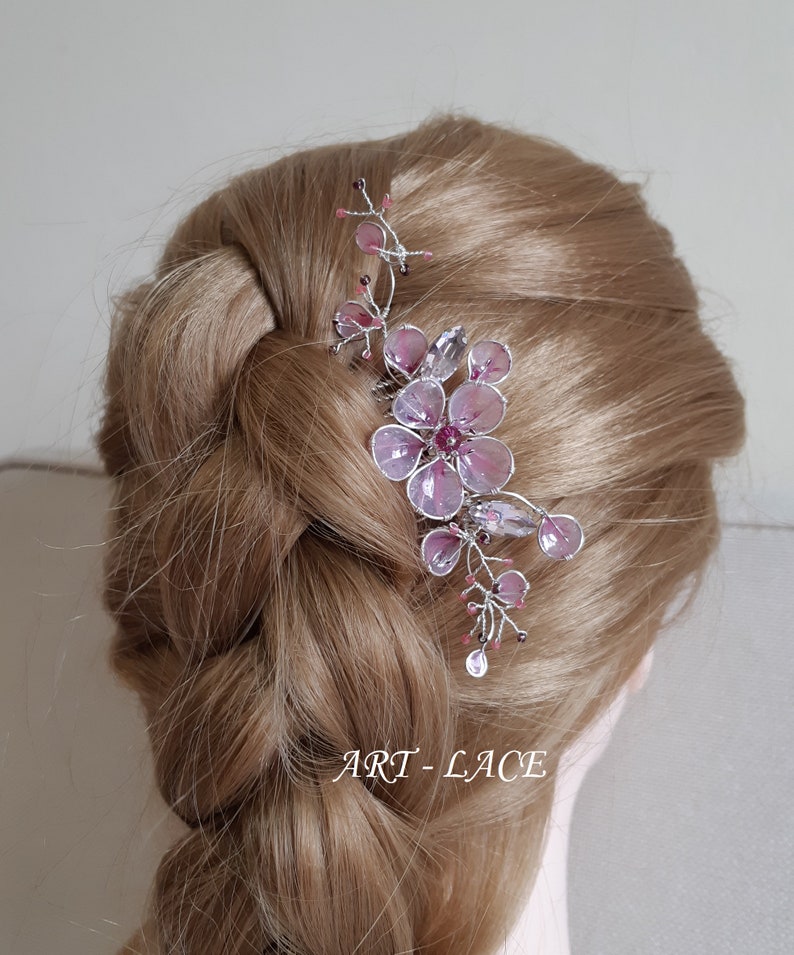 A delicate pink flower hair comb in silver finish, Japanese Kanzashi style, The central flower size 3 cm diameter. Around that is a cluster of petals, crystals and tiny seed beads. Handmade wire resin pink flowers and petals.