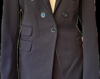 May include: A dark navy blue suit, consisting of a double-breasted blazer and matching trousers. The blazer has four buttons and two front pockets. A tag with the words "Old Money" and "Y2K" is visible.
