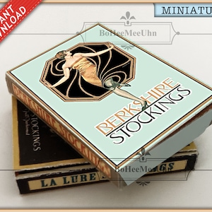 Puede incluir: Una caja miniatura de medias Berkshire con una ilustración vintage de una mujer usando medias. La caja es azul claro con letras doradas y un diseño negro y dorado. La caja está apilada sobre una caja más pequeña con el texto "La Lure" en letras doradas.