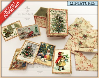 Peut inclure: Un ensemble de cartes de Noël miniatures et une boîte de rangement assortie présentant des illustrations de style vintage. Le couvercle de la boîte affiche un sapin décoré et le texte 6 Christmas Cards. Plusieurs petites cartes montrent des scènes festives avec des chats, le Père Noël, des souris et des enfants, toutes avec des bordures dorées.