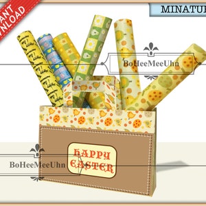 May include: A miniature paper bag with a brown front panel featuring the text HAPPY EASTER in red letters. The bag contains several rolls of patterned paper with yellow chicks, orange eggs, and green checkered designs. The bag has a top border with a chick and egg print.