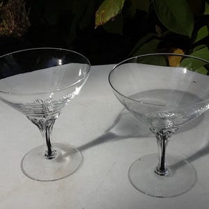 May include: Two clear glass martini glasses with a decorative stem design.