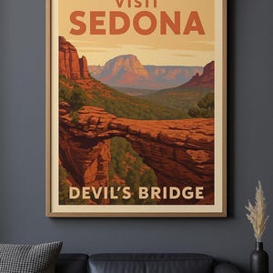 May include: A framed vintage-style travel poster for Sedona, Arizona, showing Devil's Bridge. The poster has orange text reading "VISIT SEDONA" and "DEVIL'S BRIDGE". The image depicts red rock formations and a natural bridge, evoking a sense of the American Southwest.