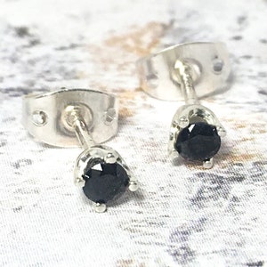 May include: A pair of silver stud earrings with black round gemstones.