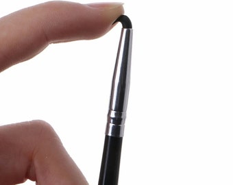 May include: A black and silver makeup brush with a bent tip. The brush is being held by a finger.