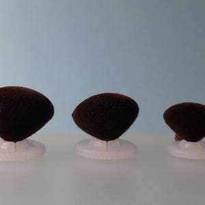 K&ouml;nnte beinhalten: Sortiment von sieben braunen Filz-Augenklappen in verschiedenen Gr&ouml;&szlig;en, jede mit einer wei&szlig;en Plastikr&uuml;ckseite.