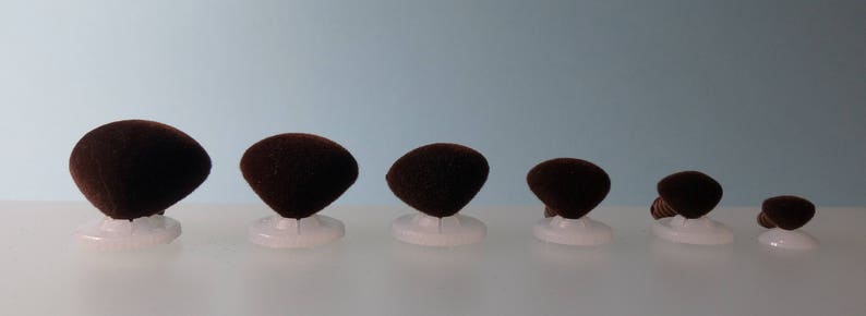 K&ouml;nnte beinhalten: Sortiment von sieben braunen Filz-Augenklappen in verschiedenen Gr&ouml;&szlig;en, jede mit einer wei&szlig;en Plastikr&uuml;ckseite.