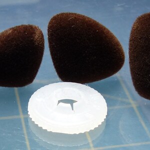 K&ouml;nnte beinhalten: Vier braune, flauschige, tropfenf&ouml;rmige Objekte und eine wei&szlig;e Plastikscheibe mit einem Loch in der Mitte.