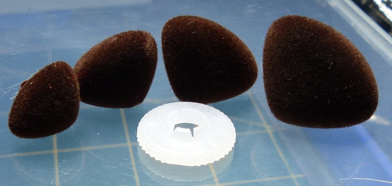 K&ouml;nnte beinhalten: Vier braune, flauschige, tropfenf&ouml;rmige Objekte und eine wei&szlig;e Plastikscheibe mit einem Loch in der Mitte.