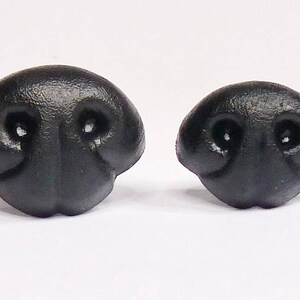 May include: Two black plastic animal noses, one larger than the other. Both have two holes for nostrils.