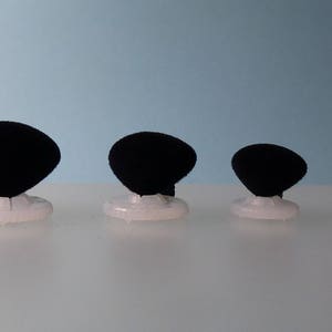 K&ouml;nnte beinhalten: Ein Set mit sieben schwarzen Samtringst&auml;ndern in verschiedenen Gr&ouml;&szlig;en, jeweils mit einem wei&szlig;en Sockel.