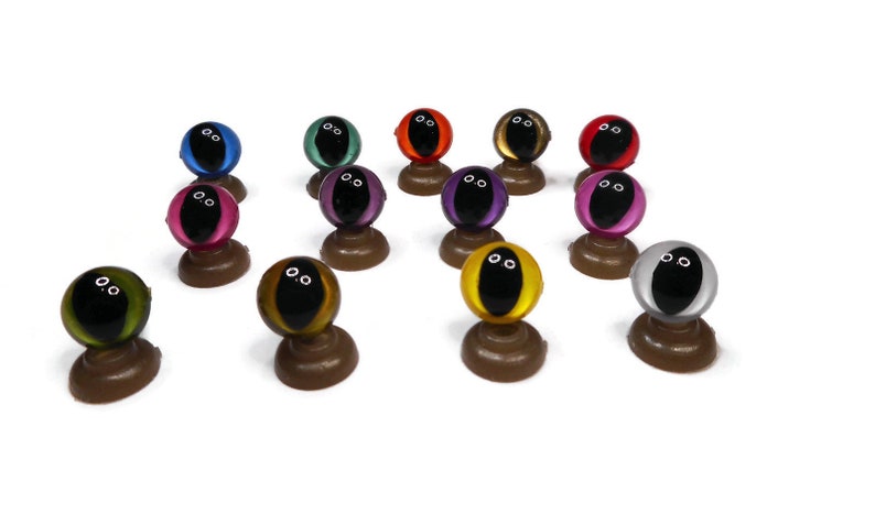 May include: Assortment of colorful plastic safety eyes with black pupils, mounted on brown plastic bases. The eyes are available in a variety of colors, including red, blue, green, purple, yellow, and silver.