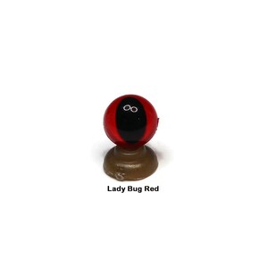 May include: Red and black plastic eye with a black pupil, mounted on a brown base. Lady Bug Red.