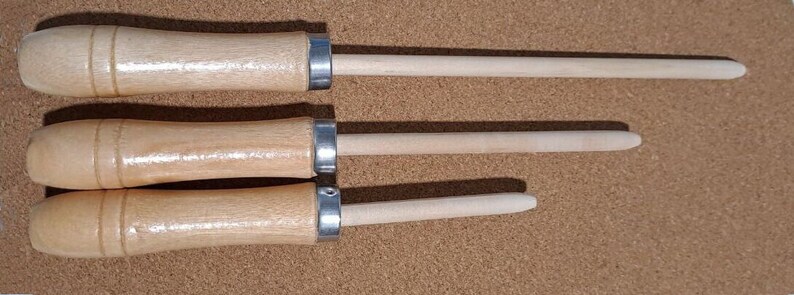 May include: Three wooden sharpening tools with metal ferrules. The tools are different lengths and have a light brown color.