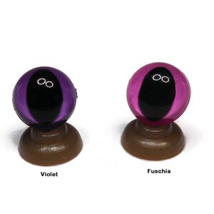May include: Two glass eyes with black pupils and white irises. The eye on the left is violet and the eye on the right is fuchsia.