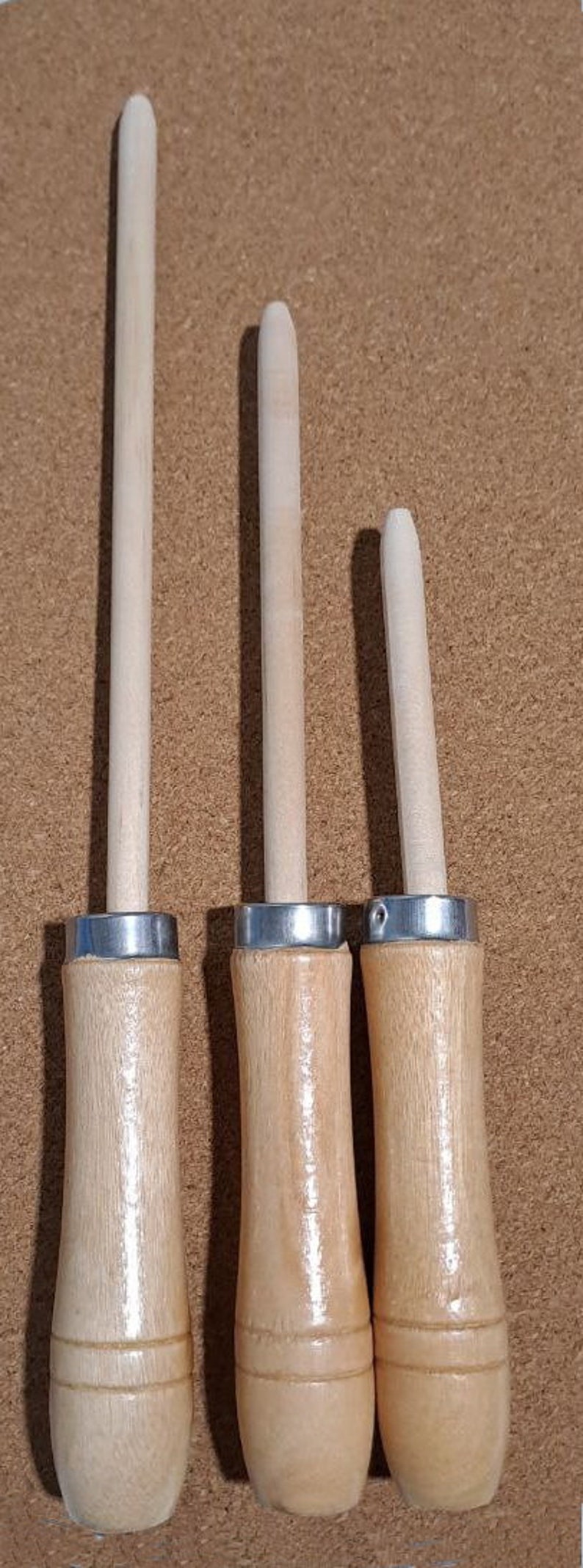 May include: Three wooden dowels with metal rings at the top. The dowels are different sizes, with the largest being about 10 inches long and the smallest being about 5 inches long.