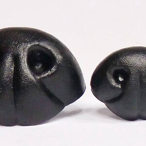 May include: Two black plastic animal noses, one larger than the other. Both have a textured surface and two small holes for nostrils.