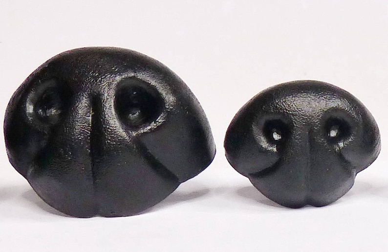 May include: Two black plastic animal noses, one larger than the other. Both have a textured surface and two small holes for nostrils.