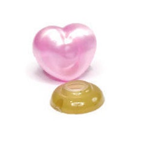 May include: A pink heart-shaped button with a gold-colored plastic base. The button is made of a shiny material and has a smooth surface.