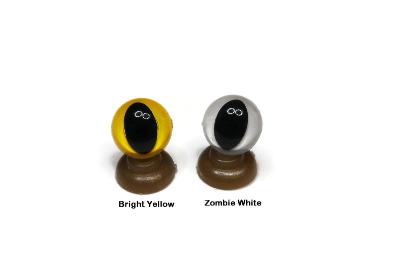 May include: Two plastic safety eyes for crafts, one bright yellow and one white. Both eyes have black pupils.