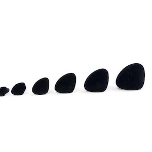 May include: A set of seven black velvet ring display stands in various sizes. The stands are shaped like small, rounded cones.