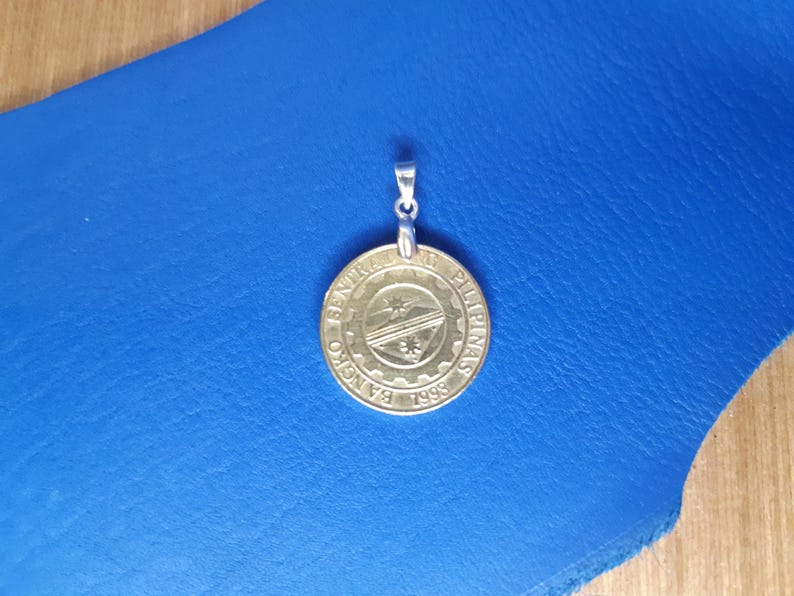 May include: A gold-coloured coin pendant with the text "Bangko Sentral ng Pilipinas 1998" and a stylised image of a ship.