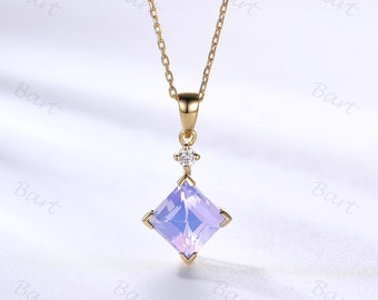 May include: A delicate gold chain necklace with a square-shaped pendant featuring a light purple gemstone and a smaller clear gemstone accent.