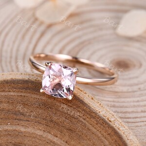 May include: A rose gold engagement ring with a square-shaped pink gemstone.