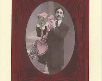 May include: A vintage postcard featuring a man in a suit holding a bouquet of flowers and a heart-shaped object. The postcard has a red border with a decorative design.