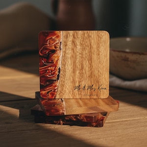 May include: Square wooden coaster with a marbled red and brown resin design on one side. The other side has a wood grain pattern and the text "Mr. & Mrs. Kane FOREVER" in black script. Coasters are stacked on top of each other.