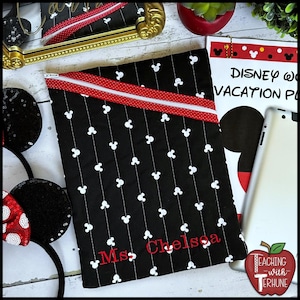May include: Black zippered pouch with white Mickey Mouse icons and vertical lines. A red stripe with a white polka dot pattern accents the top. The name "Ms. Chelsea" is embroidered in red. A "Disney Vacation Plan" notepad and a tablet are visible.