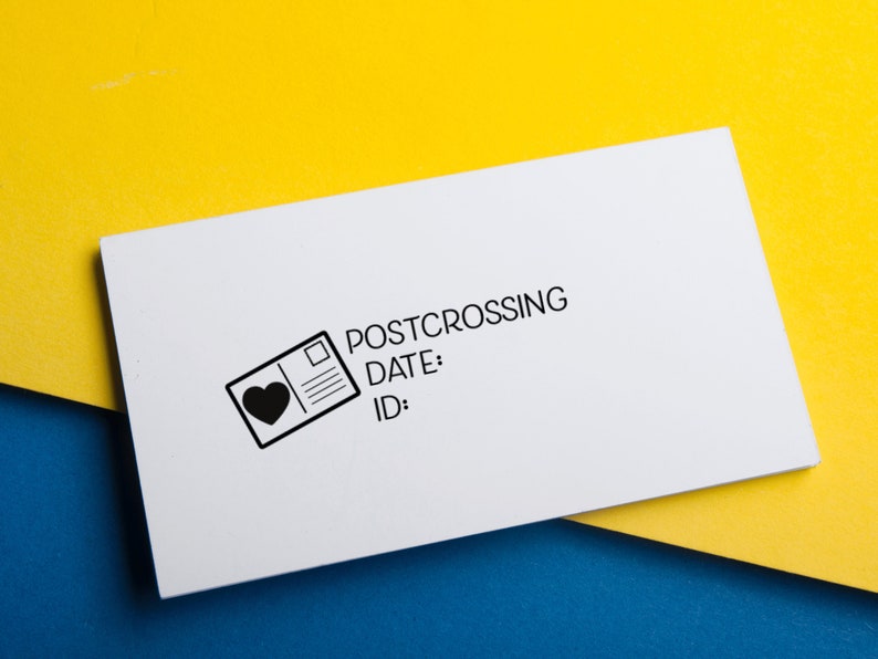 May include: A rectangular white rubber stamp featuring a black graphic of a postcard with a heart icon. The text reads POSTCROSSING, DATE:, and ID:. The stamp is designed for marking mail and correspondence with clear, bold black lettering and lines.