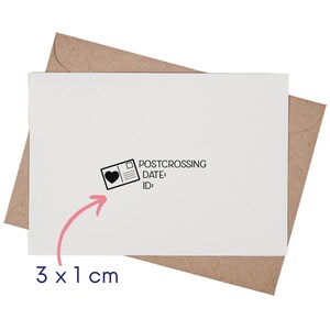 May include: A white rectangular card placed on a brown envelope. The card features a black ink stamp design of a postcard with a heart icon, the text POSTCROSSING, DATE:, and ID:. A pink arrow points to the stamp with the text 3 x 1 cm.