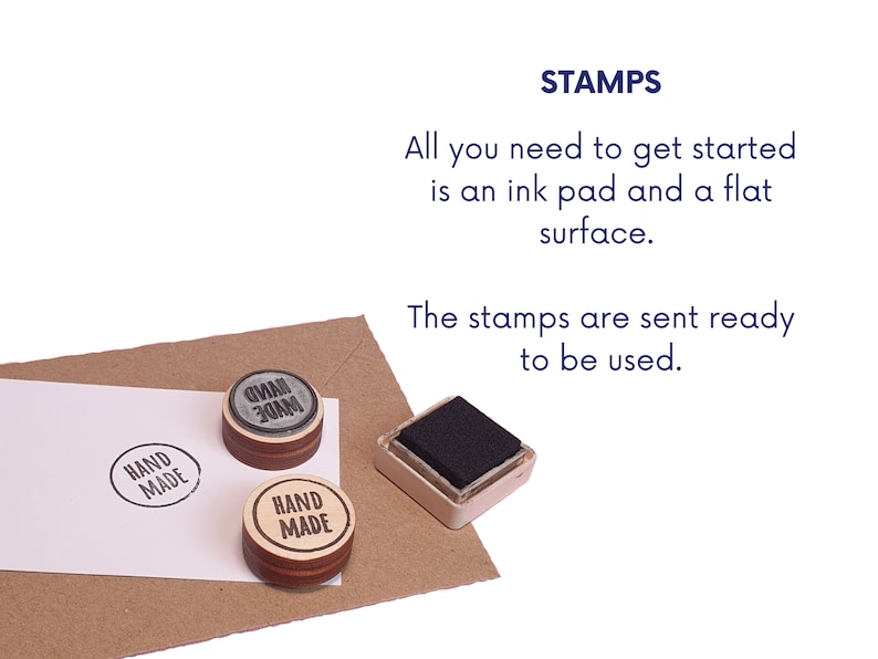 May include: Two wooden stamps with the text "HAND MADE" in black ink, one with a gray background and one with a natural wood background. A black ink pad is also shown.