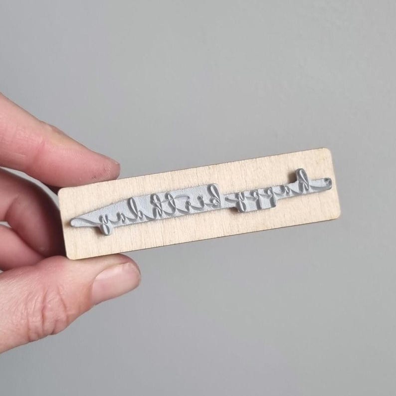 May include: Wooden stamp with the text "Happy Birthday" in a cursive font.