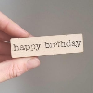 Pode incluir: Um letreiro de madeira com o texto "happy birthday" impresso em preto.