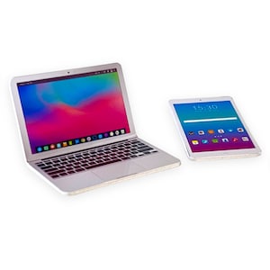 Pode incluir: Um computador portátil prateado com um fundo abstrato colorido na tela e um tablet prateado com um fundo azul e roxo e a hora 15:30 exibida na tela.