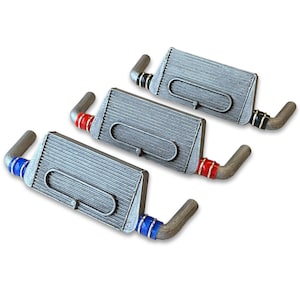 May include: Three silver-coloured metal intercooler models with red, blue and black hoses. The models are arranged in a row, with the red hose model at the front, the blue hose model in the middle and the black hose model at the back.