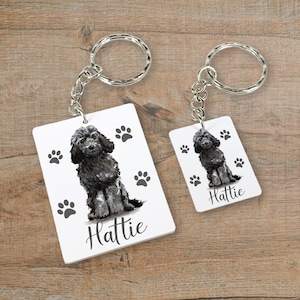 May include: Two black and white dog keychain charms with paw prints and the name "Hattie" on them.