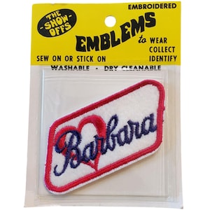 May include: White iron-on patch with red border and a blue embroidered heart and the name "Barbara" on a yellow card with the text "Embroidered Emblems to Wear Collect Identify Sew on or Stick on Washable Dry Cleanable The Show Offs"