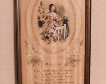 May include: A framed vintage print with a poem about motherhood. The print features a woman in a white dress sitting on a bench in a garden. The poem reads "Mother Dear, God sent the birds and sunshine to gladden all the world: He sent the foliage and flowers in radiance unfurled: He sent the June, the stars, the moon, The pearly dewdrops sweet. And then He sent you, Mother Dear, To make it all complete."